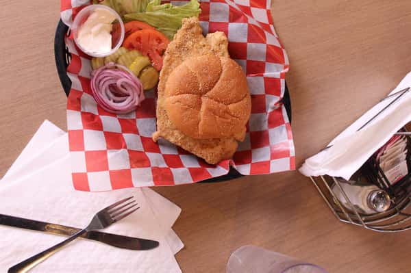 fried chicken sandwich with greens to the side