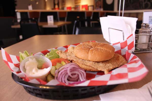 fried chicken sandwich with greens to the side