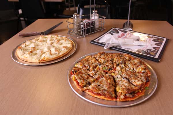 two pizza pies with utensils and menu