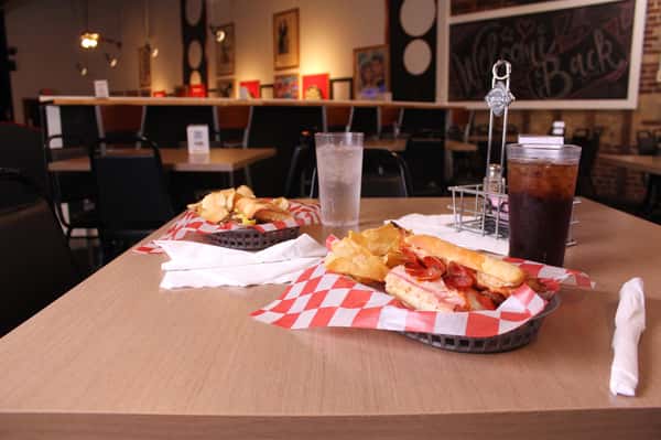 pepperoni hero with chips in a basket with cola and water