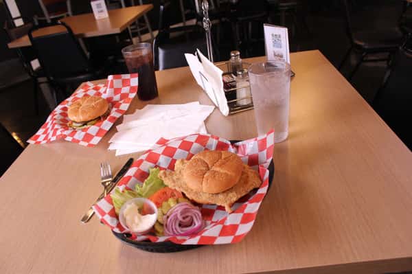 fried chicken sandwich with hamburger and cola in back