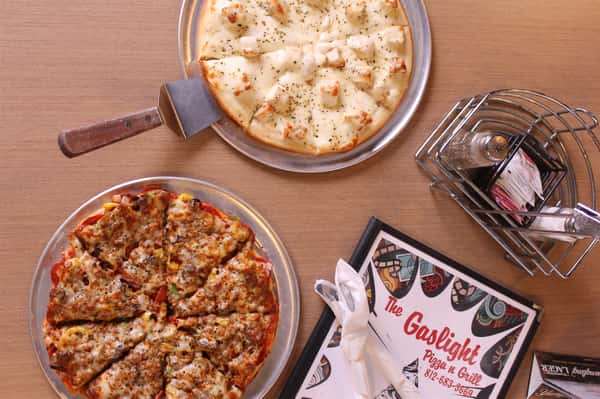 two pizza pies with utensils and menu