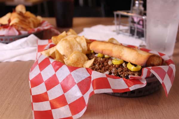 philly cheesesteak with chips in a basket with cola and water