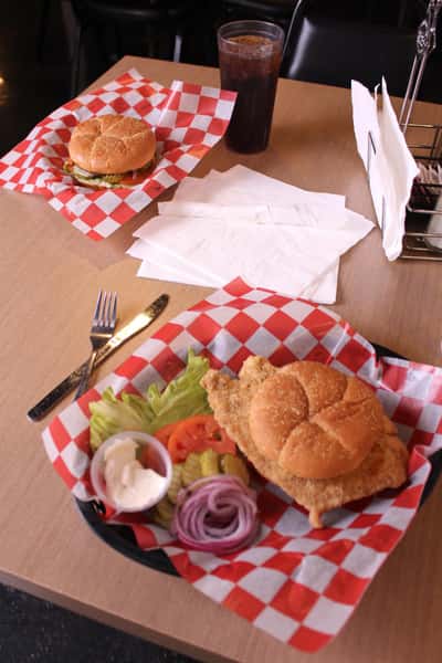 fried chicken sandwich with hamburger and cola in back