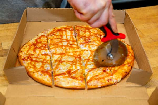 Fresh pizza being sliced with a cutter at The Gaslight Pizza & Grill in Huntingburg, Indiana