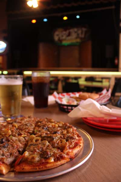 pizza pie with cola and beer in front of stage