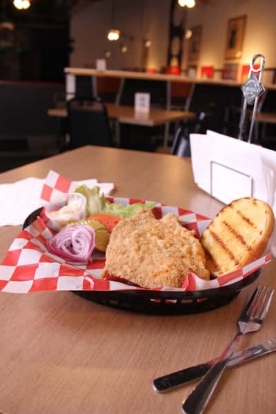 fried chicken sandwich with greens to the side