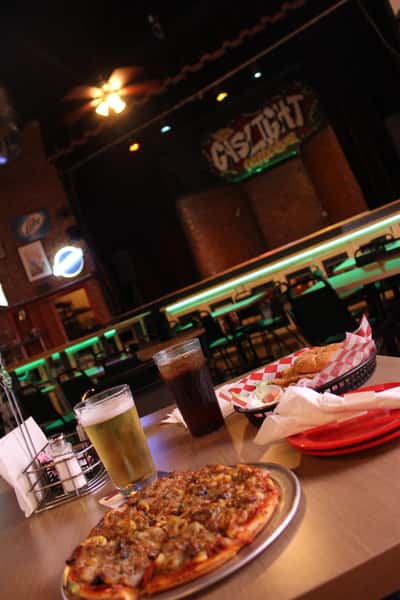 pizza pie with cola and beer in front of stage