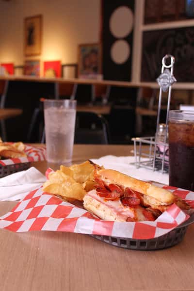 pepperoni hero with chips in a basket with cola and water