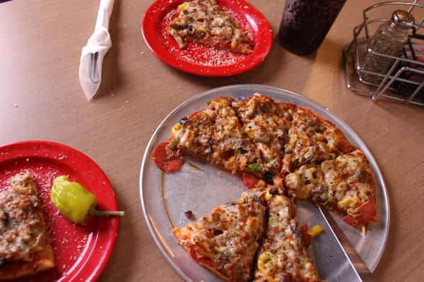 pizza pie with slices on plates