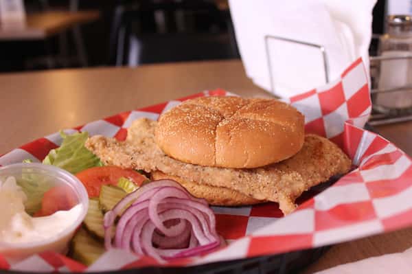 fried chicken sandwich with greens to the side