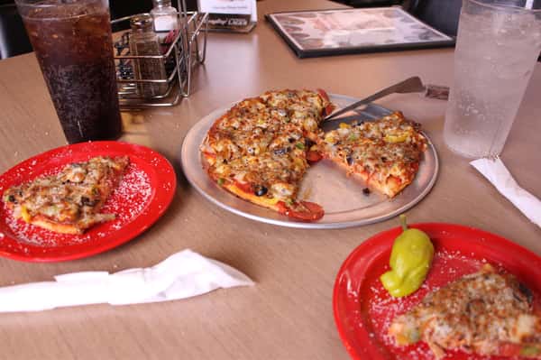 pizza pie with slices on plates