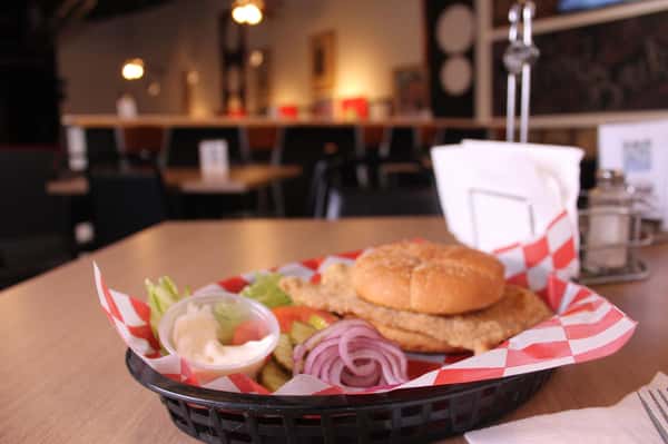 fried chicken sandwich with greens to the side