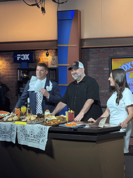 Fox 10 Arizona morning show segment featuring Foley Ranch BBQ owners presenting smoked meats, cocktails, and signature menu items in a live television studio.