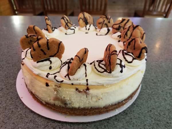 A cheesecake with cookies and drizzled chocolate on top
