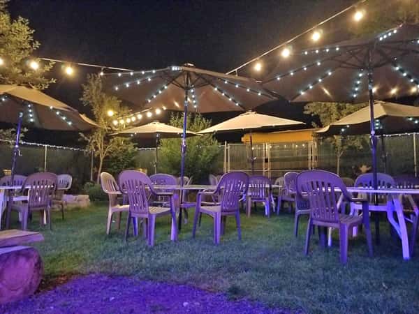 Outdoor seating area at night with string lights on over the tables and umbrellas