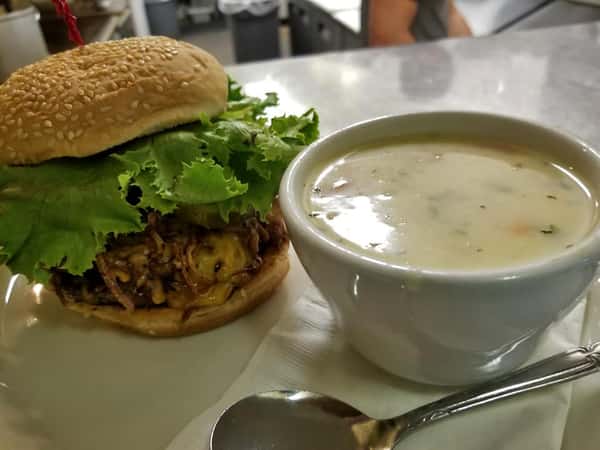 A cheeseburger with fried onions, and lettuce with a side of creamy soup