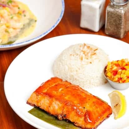 Glazed grilled salmon fillet served with steamed white rice and tropical mango salsa — elegant seafood dish with Latin-inspired flavors.