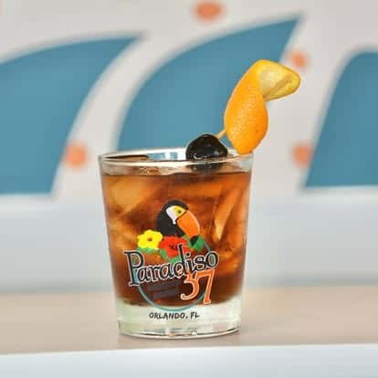 Whiskey-based cocktail on the rocks in a Paradiso 37 glass, garnished with an orange twist and dark cherry skewer for a refined tropical touch.