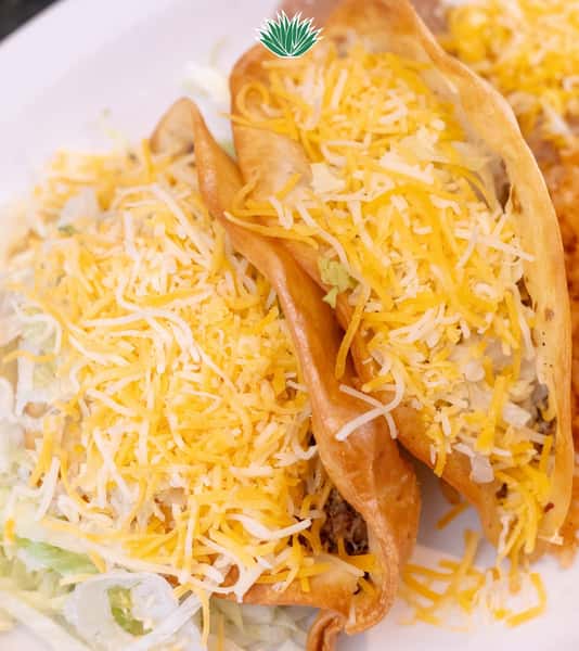 Close-up of a crispy taco filled with seasoned meat, lettuce, and shredded cheese