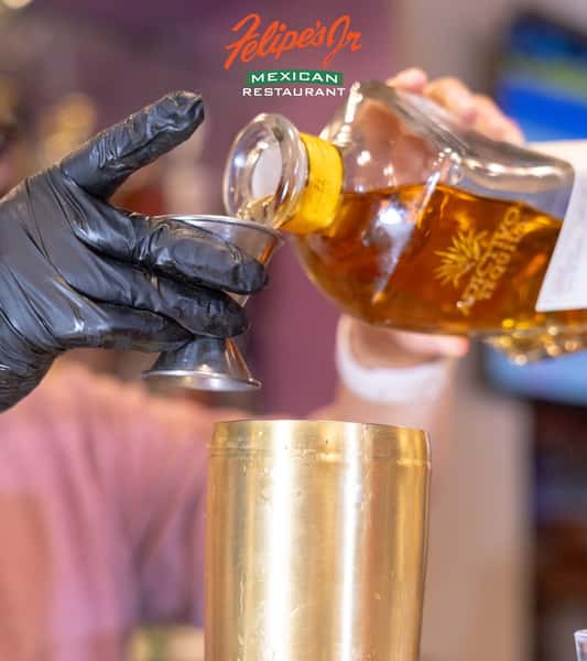Tequila being poured into a shot glass at the restaurant bar