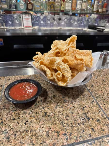 Crispy chicharrones served with a side of red salsa