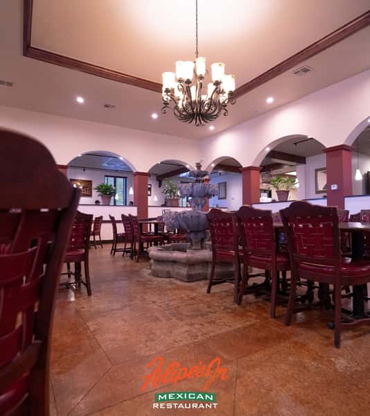 Interior dining area with red seating and arched architectural details at Felipe's Jr.