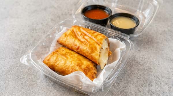 Two golden-brown crispy spring rolls with melted white cheese filling, served in a plastic container with two dipping sauces.