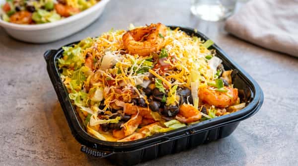 Shrimp burrito bowl with shredded cheese, lettuce, black beans, and salsa in a black plastic container.