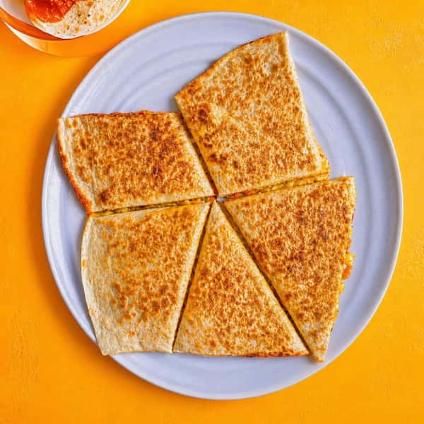 kids cheese quesadilla sliced into triangles and served on a white plate with a bright yellow background