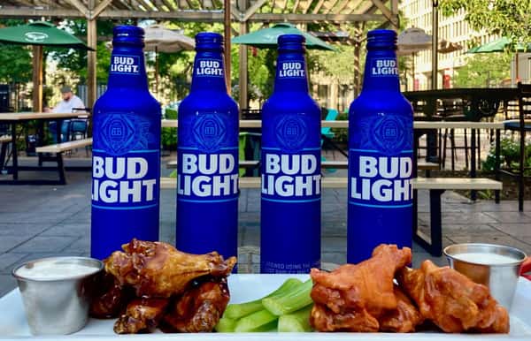 4 bud light bottles with chicken dishes in front of them