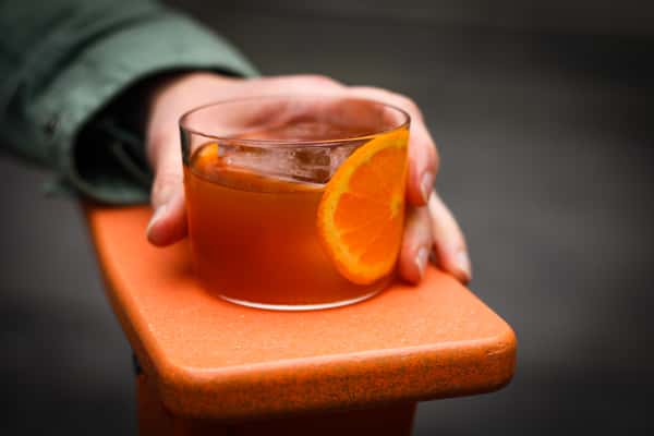 short glass of drink with orange slice inside