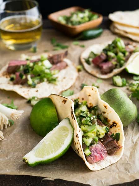 Grilled steak tacos with fresh cilantro-lime salsa, chopped onions, and tender slices of beef on charred flour tortillas—classic carne asada street tacos.