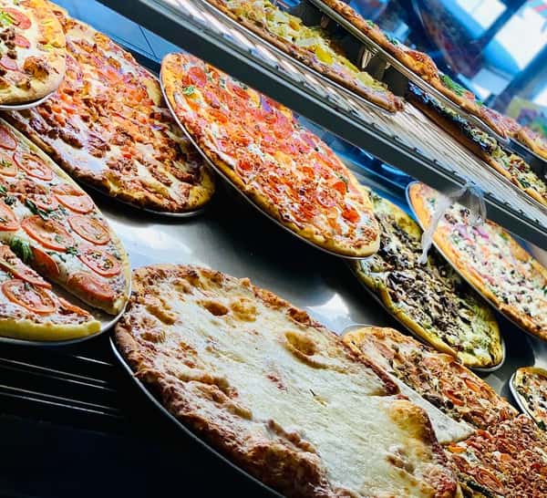 Freshly baked gourmet pizzas on display in a glass case at an Italian pizzeria, featuring pepperoni, margherita, veggie, and cheese pizzas with golden crusts and melted mozzarella, showcasing a vibrant casual dining restaurant atmosphere.
