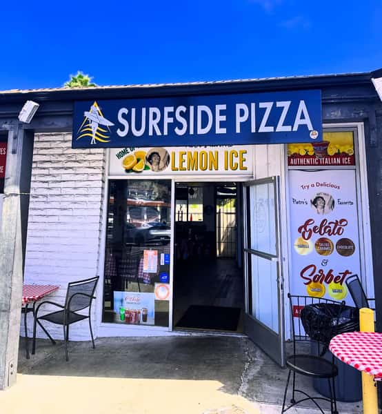 Exterior storefront of Surfside Pizza featuring bold blue signage, lemon ice and authentic Italian ice posters, and a welcoming entrance to a casual beachside Italian pizzeria.