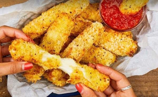Crispy mozzarella sticks pulled apart with melted cheese stretch, served with marinara dipping sauce at Surfside Pizza, a casual Italian dining favorite.