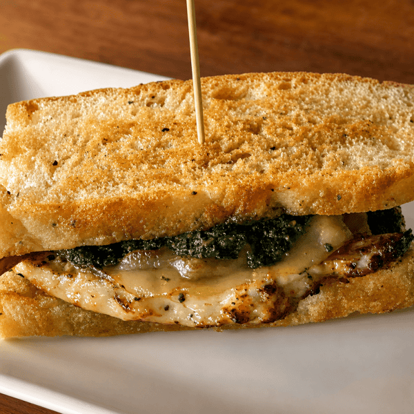Grilled panini sandwich with pesto and chicken, sliced in half and secured with a skewer