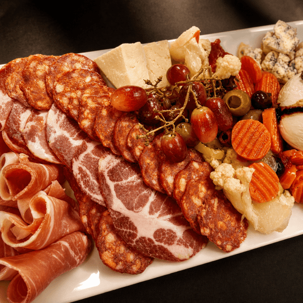 Charcuterie board with cured meats, cheese, grapes, and olives