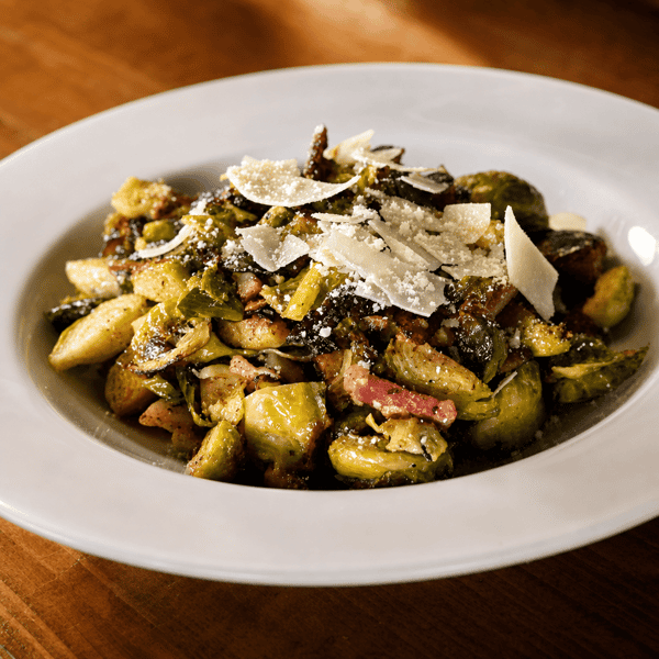 Roasted brussels sprouts topped with shaved parmesan in a white bowl