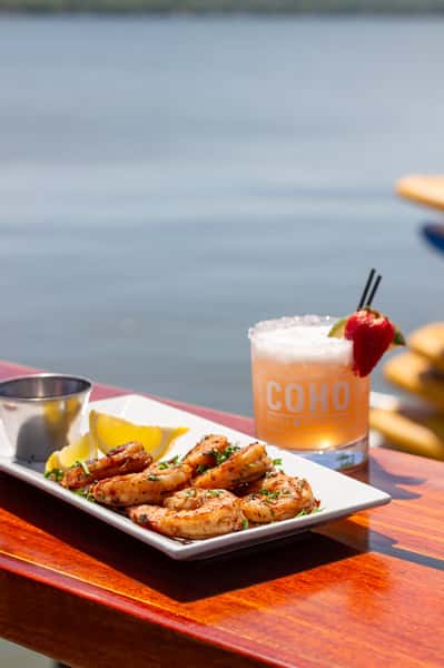 Chicken wings served with a cocktail on a waterfront table