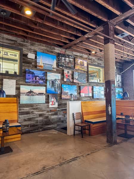 Restaurant dining area with framed photos on a stone wall and wooden booth seating