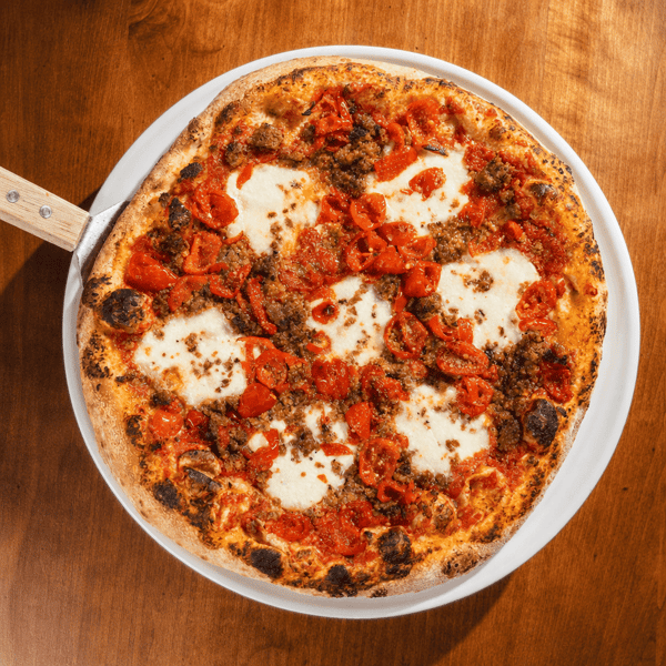 Margherita pizza topped with fresh mozzarella, tomatoes, and Italian sausage crumbles