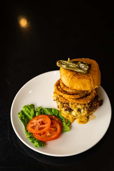 the big dirty burger. beef patty, house-made chili, queso, guacamole, crispy onions, roasted bell peppers, avocado, lettuce, tomato, pickles, chipotle aioli, all served on a sourdough bun