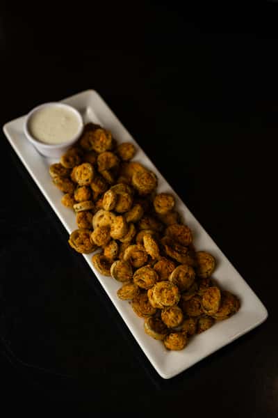 fried okra sit on a white plate with house-made ranch on the side.