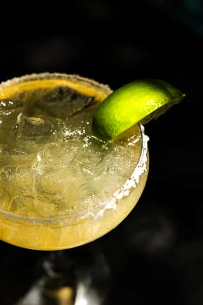 classic margarita in a glass with a salted rim and lime wedge garnish.