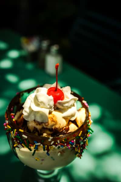 classic sundae with vanilla ice cream, chocolate drizzle, rainbow sprinkles, whipped cream, and a cherry on top.