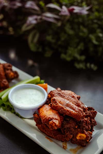 A plate of crispy wings with a side of celery, carrots, and house-made ranch.