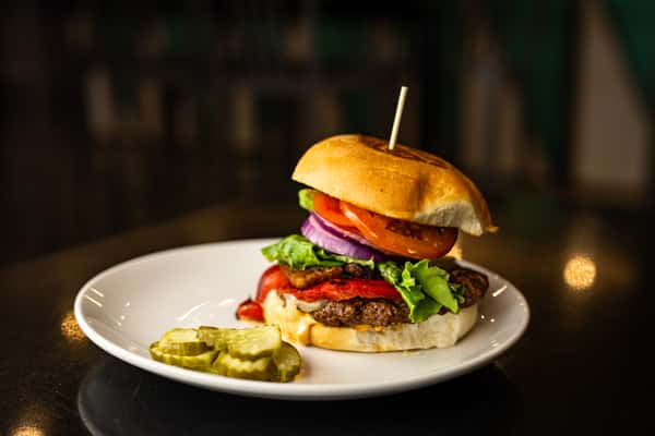 Burger with a brioche bun, onions, peppers, lettuce, and all the fixings.