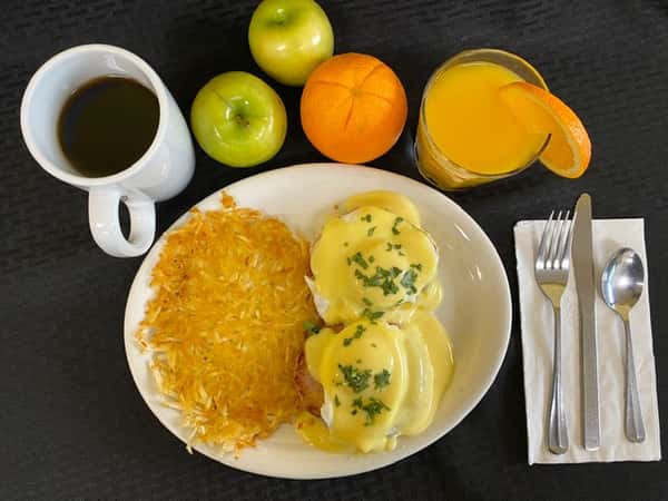 Boulevard Cafe's hearty breakfast featuring creamy Eggs Benedict, golden hash browns, fresh orange juice, and coffee, all on a dark background.