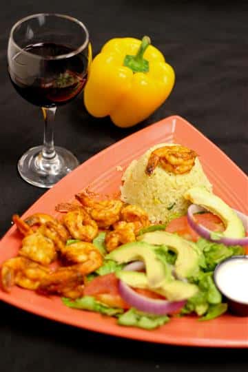 Shrimp with rice and salad topped with tomatoes, red onions, and avocados